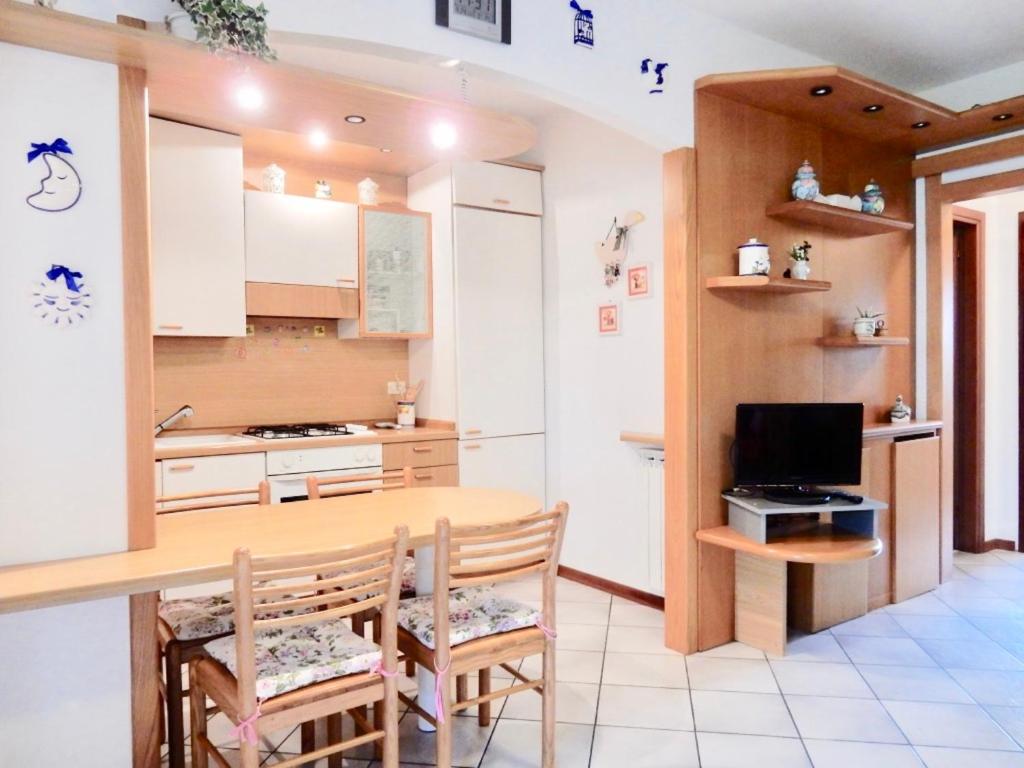 cocina con mesa de madera y sillas y TV en Appartamento Le Mimose, en Viareggio