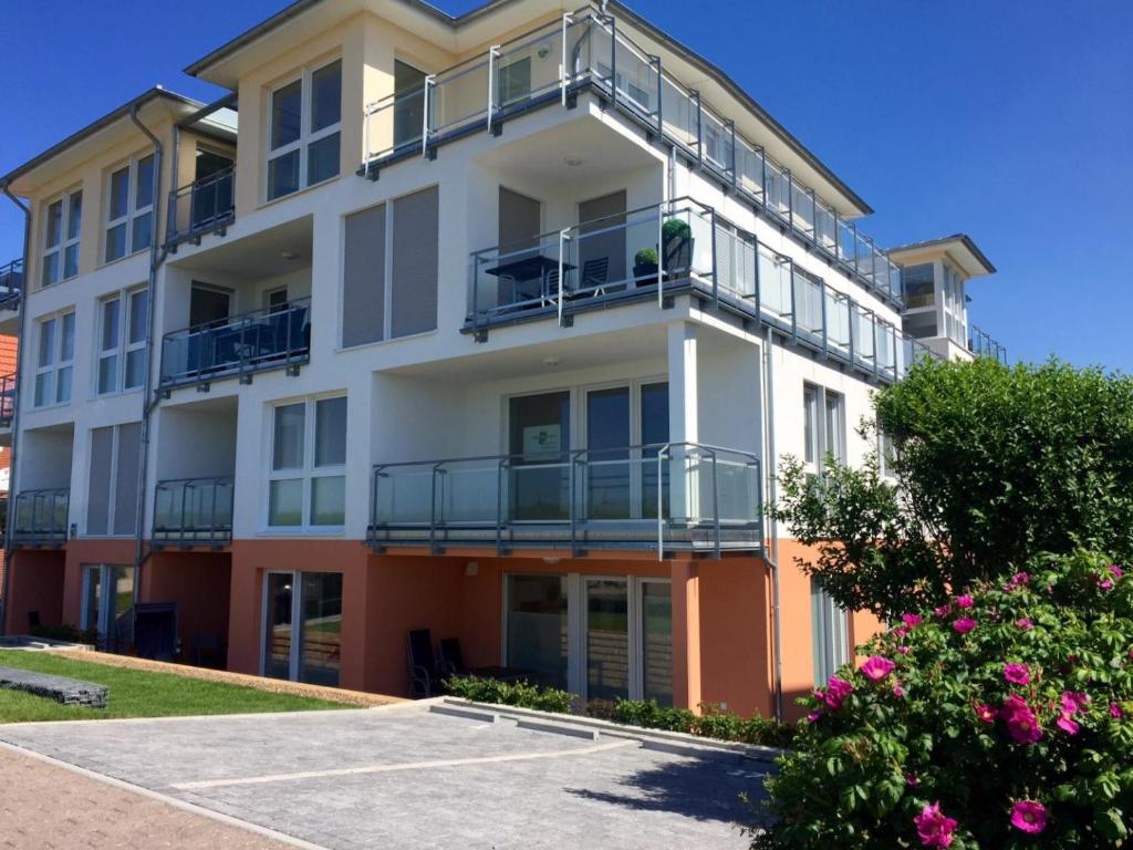 un edificio de apartamentos blanco con balcones y flores rosas en Residenz Windjammer Whg.2, en Cuxhaven