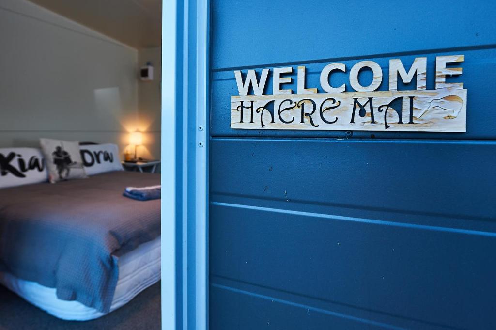 ein Schlafzimmer mit blauer Wand und einem Willkommensschild in der Unterkunft WanaHaka - Lake Wanaka & Town at your door in Wanaka