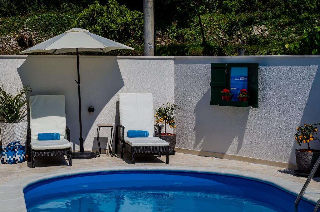 a swimming pool with two chairs and an umbrella at Apartments Orange Tree in Cavtat