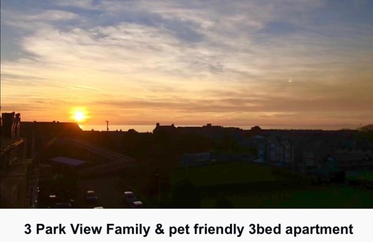 un coucher de soleil dans une ville avec le soleil dans le ciel dans l'établissement 3 Park View, à Barmouth
