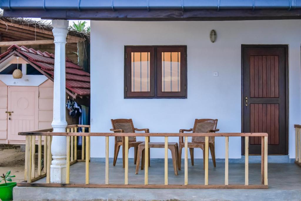 Saman Beach Guest House في غالي: طاولة وكراسي خشبية على شرفة