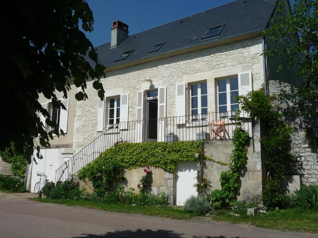 a white brick house with a balcony and ivy at En bord de Loire in Pouilly-sur-Loire