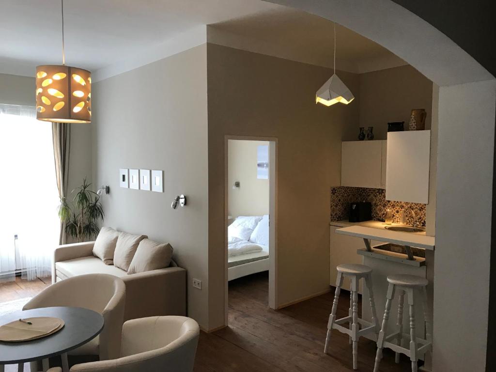 センテンドレにあるFőtér Apartmanház Szentendreのリビングルーム(ソファ、テーブル付)、キッチンが備わります。