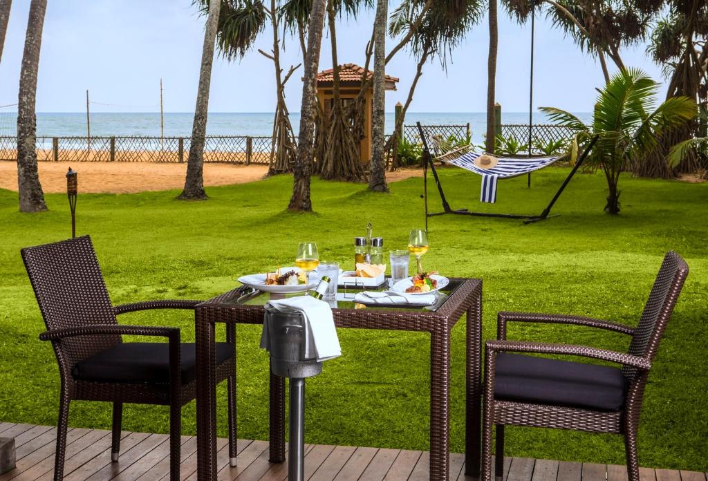 uma mesa com um prato de comida e copos de vinho em Royal Palms Beach Hotel em Kalutara