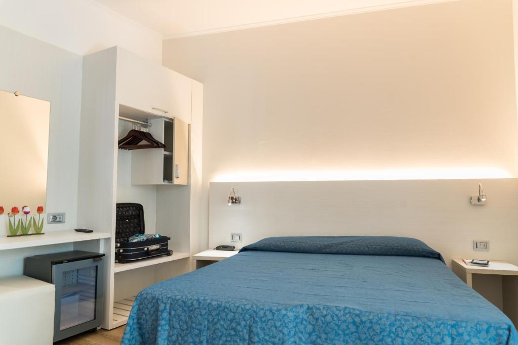a bedroom with a blue bed and white walls at Hotel Mara in Lido di Jesolo