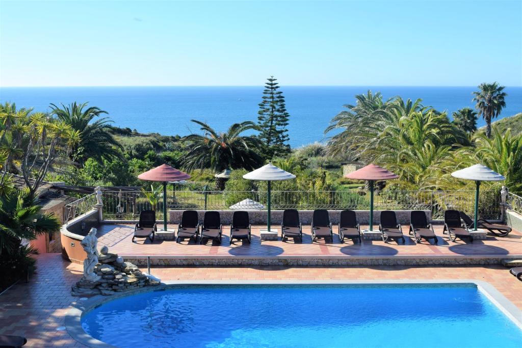 een zwembad met stoelen en parasols en de oceaan bij Quinta do Mar - Country & Sea Village in Luz