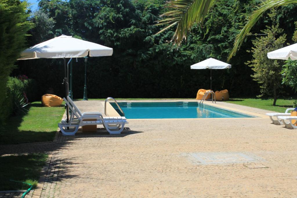 a swimming pool with two chairs and an umbrella at Quinta da Boa Ventura in Bragança