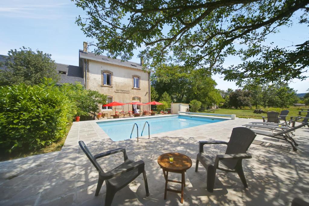 una piscina con sillas y una mesa junto a una casa en La Gare aux Anes, en Combe-Redonde