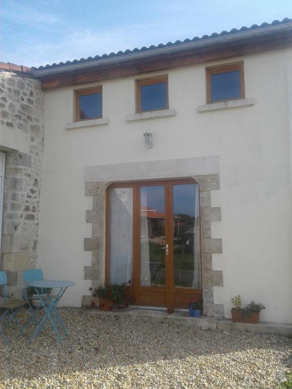 une maison blanche avec une porte en bois et une table dans l'établissement Fleur Du Soleil, à Agudelle