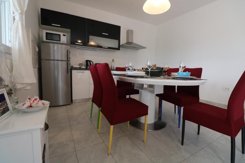 kuchnia ze stołem i czerwonymi krzesłami w pokoju w obiekcie Apartman La maison w mieście Zadar