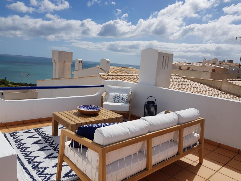 a balcony with a table and chairs on a roof at Casinha Manta in Salema