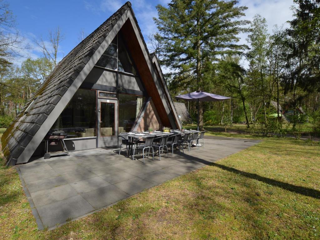 a house with a triangular roof with tables and chairs at Holiday home with large terrace in Stramproy