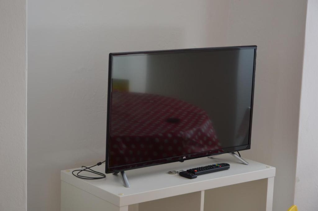 telewizor z płaskim ekranem siedzący na białej szafce w obiekcie Appartamento Sunrise - Centro Storico N1 w mieście Riva del Garda