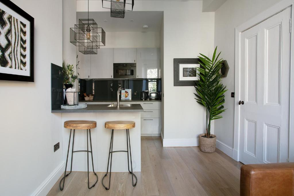 a kitchen with two bar stools and a sink at Holyrood Park City Centre Apartment in Edinburgh