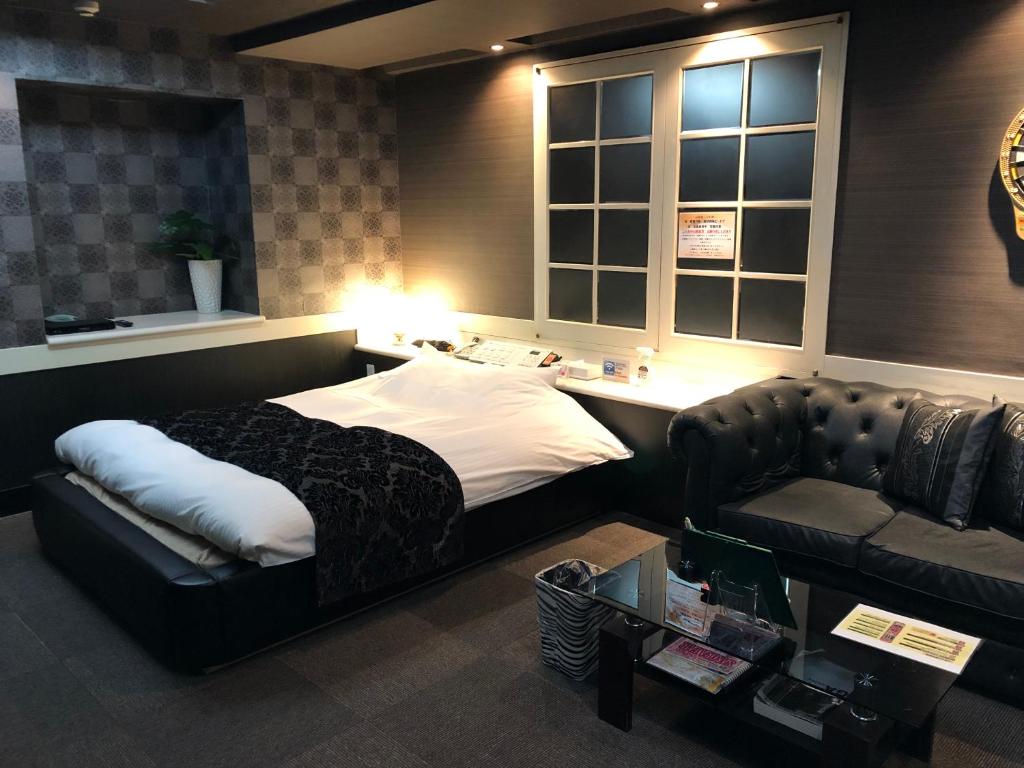 um quarto com uma cama, um sofá e uma mesa em ホテル フェリエ hotel for adults em Hachioji