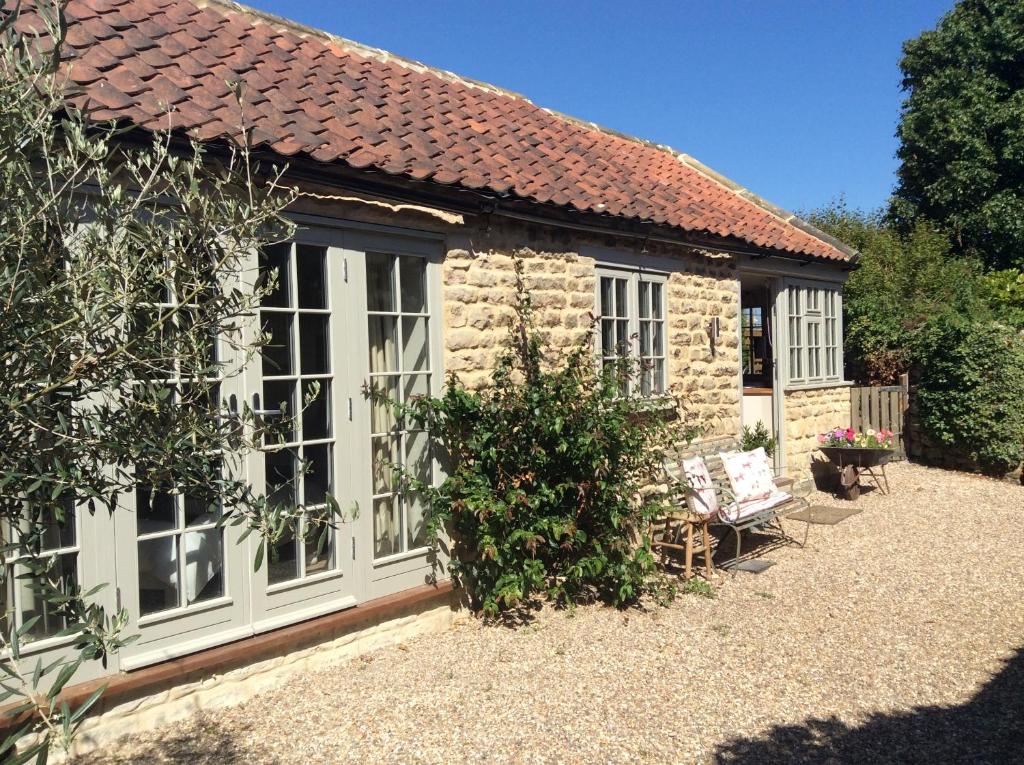 Casa de campo de piedra con ventanas y banco frente a ella en Annex Fishers Yard en York