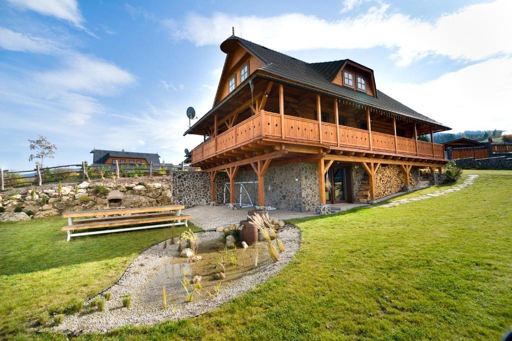 a large wooden house on top of a green field at Chata Zlata in Liptovská Štiavnica
