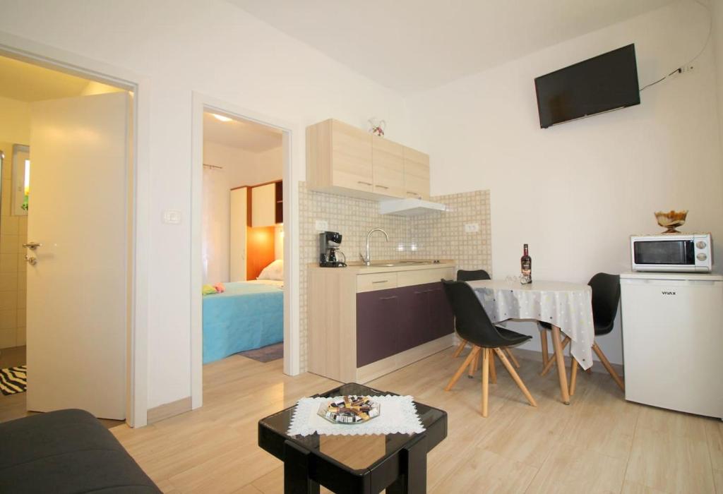 Habitación con cocina y sala de estar con mesa. en Apartment Noemi in city center, en Poreč