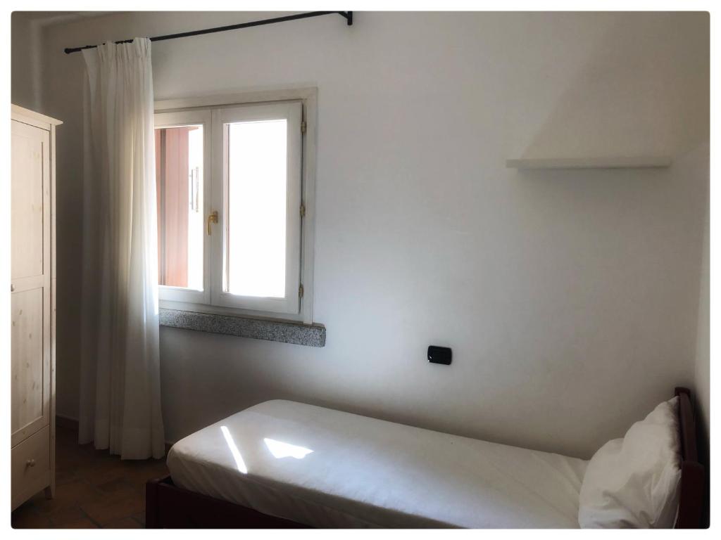 biały pokój z łóżkiem i oknem w obiekcie Incanto Apartment Golfo Aranci w mieście Golfo Aranci