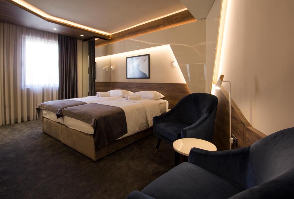 um quarto de hotel com uma cama e duas cadeiras em Garni Hotel Boutique 25h em Niš
