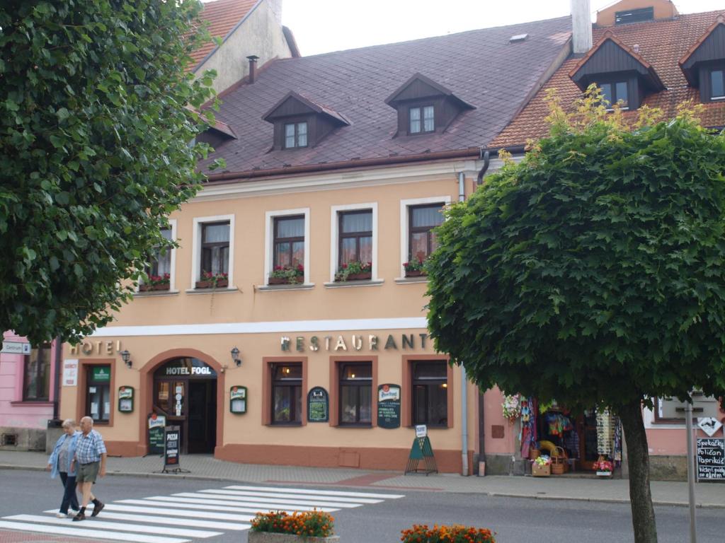 un edificio en una calle con gente cruzando una calle en Hotel Fogl, en Nová Bystřice