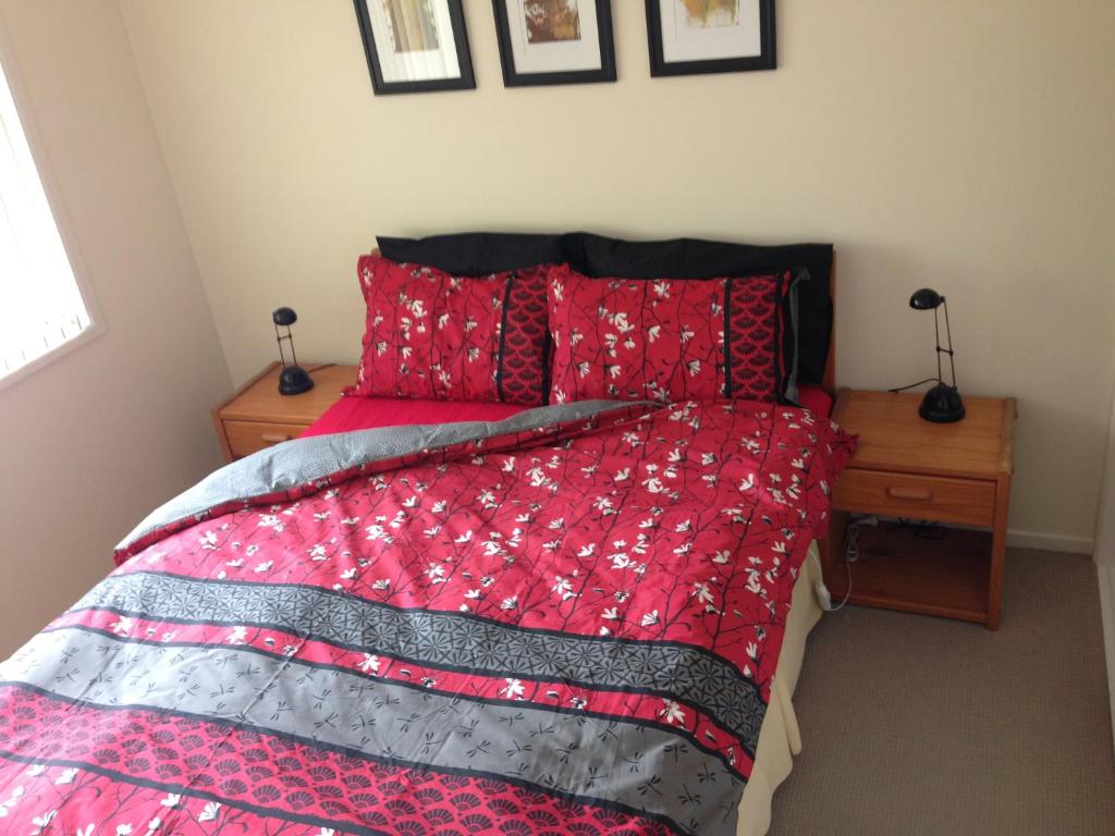 a bedroom with a red bed with two night stands at Cosy Home in Yandina in Yandina