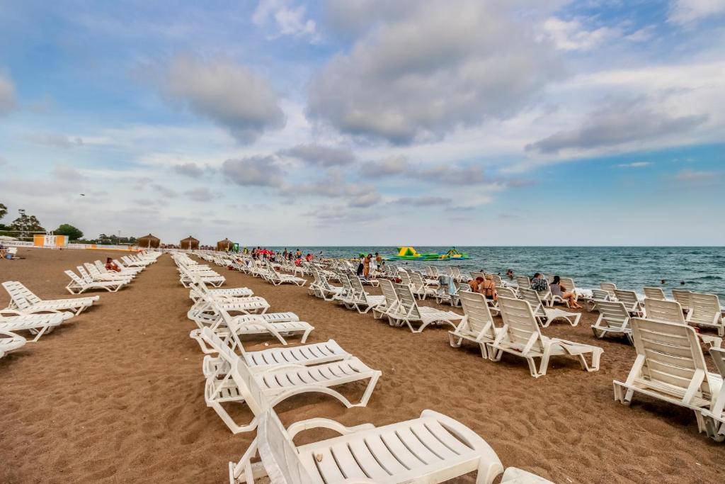 a row of white lawn chairs on a beach at Lara Park Hotel in Antalya