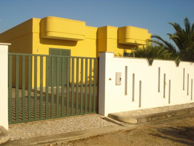 een wit hek voor een geel huis bij La casa di Anna in Torre Lapillo