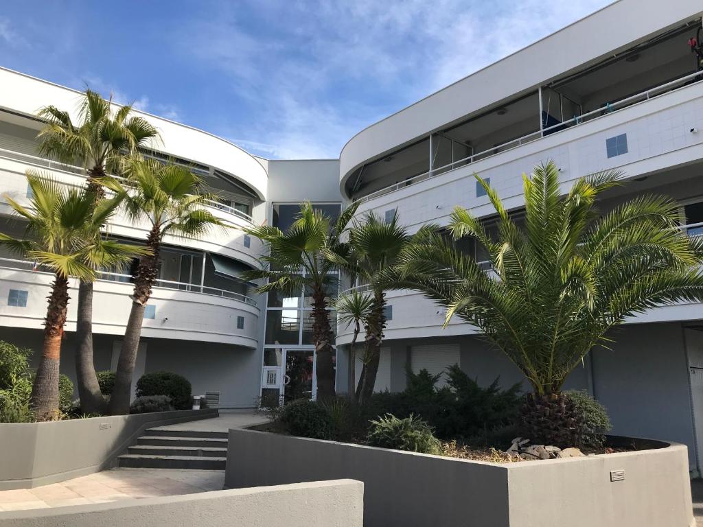 un bâtiment avec des palmiers devant dans l'établissement AcquaMarina, à Villeneuve-Loubet