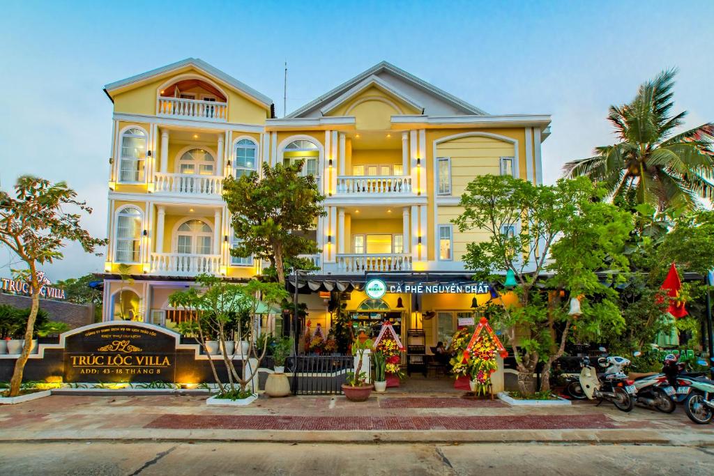 un gran edificio amarillo con árboles delante de él en Truc Loc Villa en Hoi An