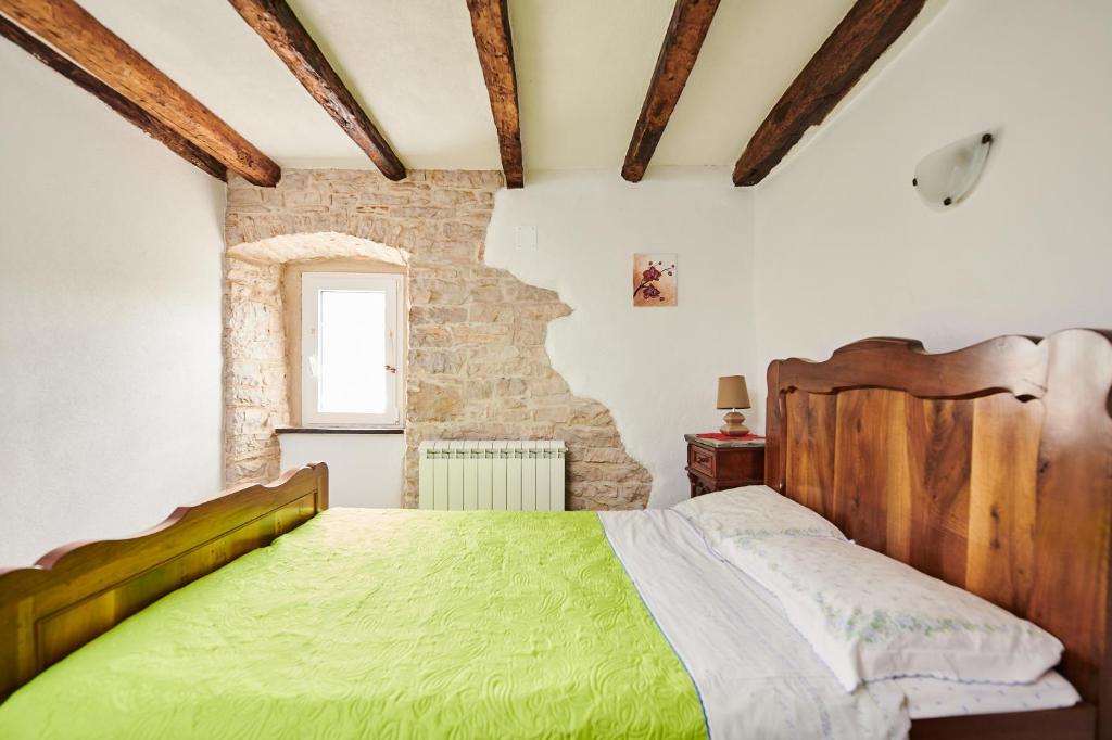 a bedroom with a green bed and a brick wall at App Lidia in Grožnjan