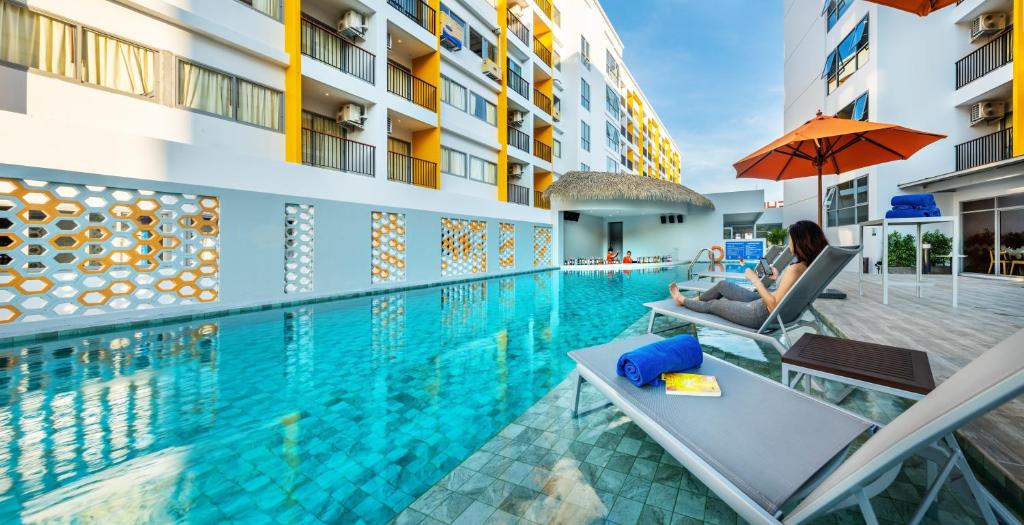 una donna seduta su una sedia accanto alla piscina di Beehive Boutique Hotel Phuket a Phuket