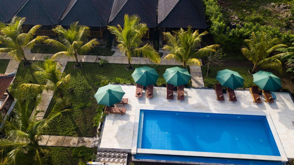 una vista aérea de una piscina con sombrillas verdes en Ruji Ananta Cottage en Nusa Penida