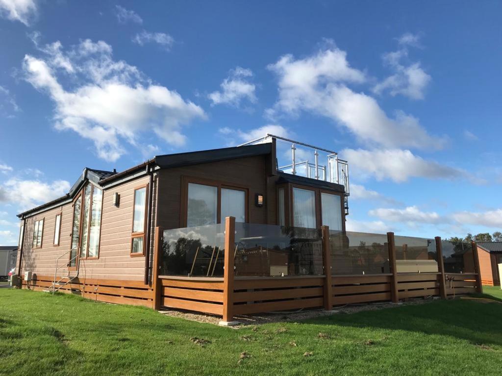 a modular house with a fence on the grass at Hot tub hols in Bear Lodge with roof terrace in Tattershall