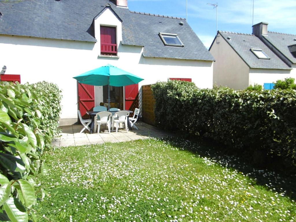 une maison blanche avec un parasol vert dans la cour dans l'établissement Maisonnette Malou, à Sarzeau