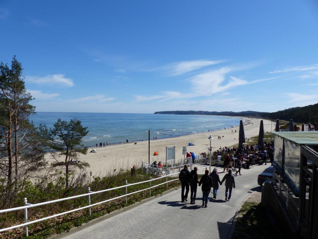 a group of people walking down a sidewalk next to a beach at Ferienwohnung Seewald in Ostseebad Sellin