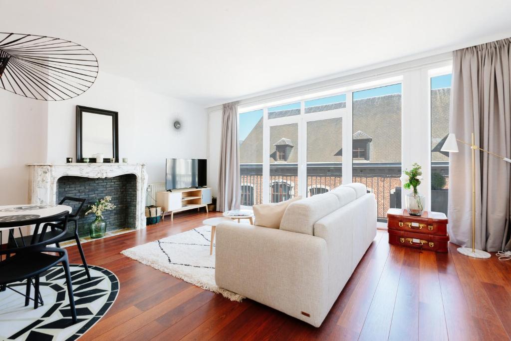 ein Wohnzimmer mit einem weißen Sofa und einem Tisch in der Unterkunft Luxury Apart' MONS City Center with Terrace in Mons