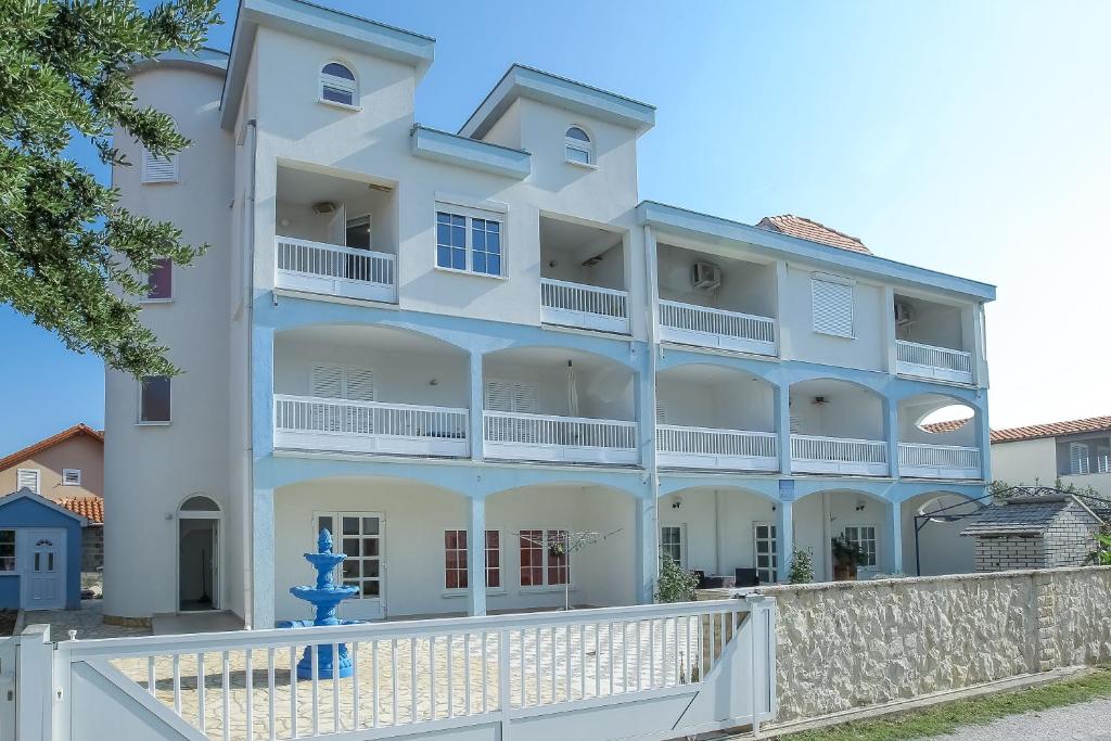 a large white building with a white fence at SENITA's Rooms & Apartments in Nin