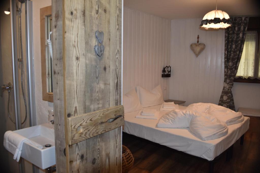 a bedroom with a white bed and a sink at La Molinela B&B in Folgaria