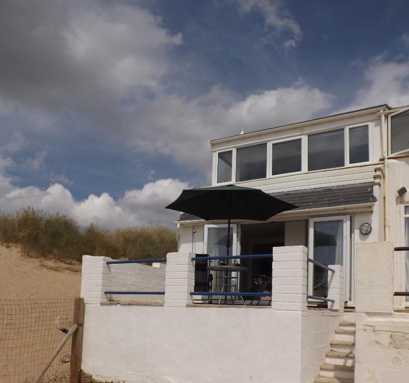 a house with an umbrella on the beach at Seagull's Crest in Camber