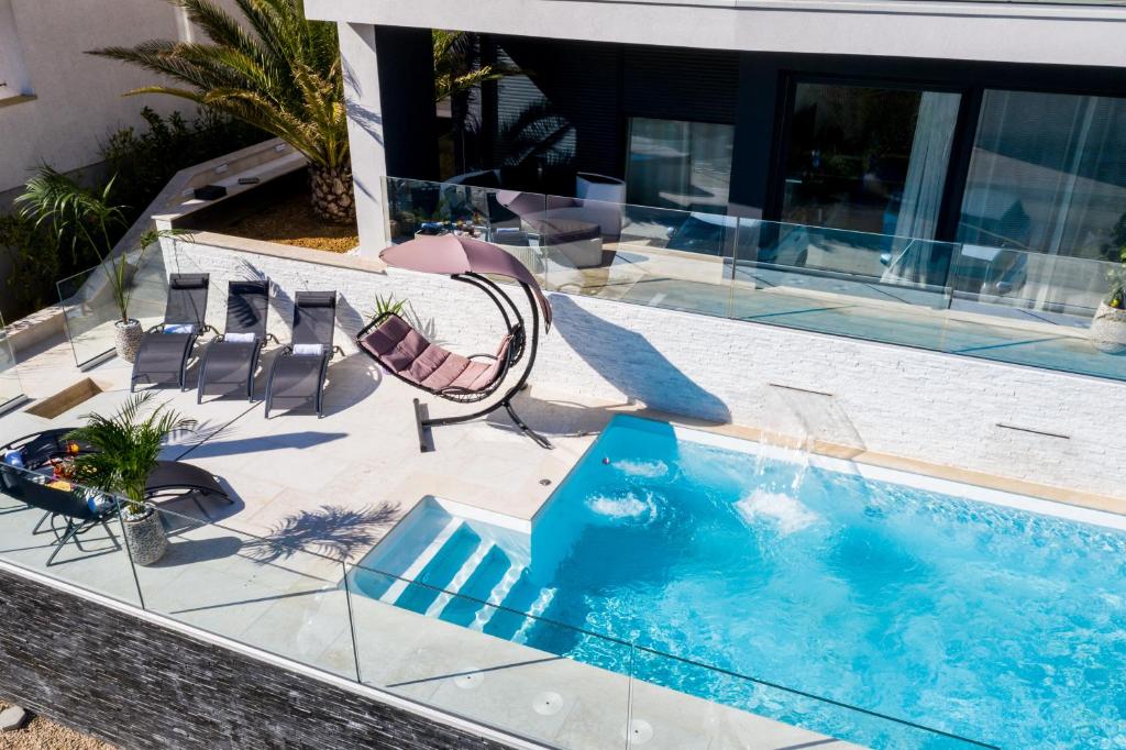 a pool with a slide and chairs and a swimming pool at Villa Valis in Baška