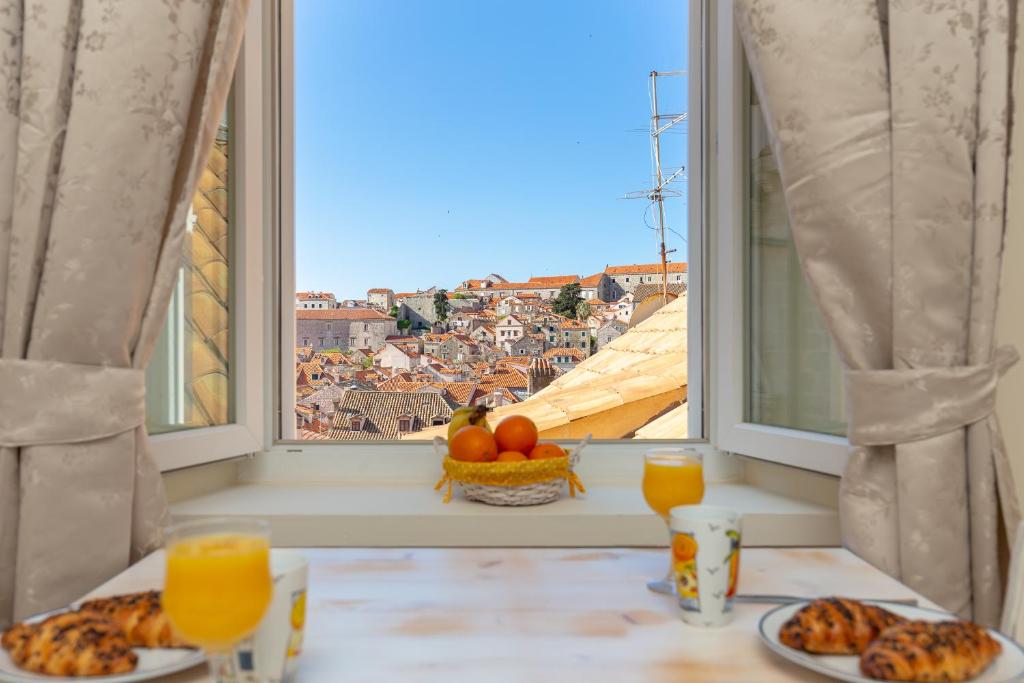 a table with plates of food and a window with a view at Siesta Ragusa in Dubrovnik