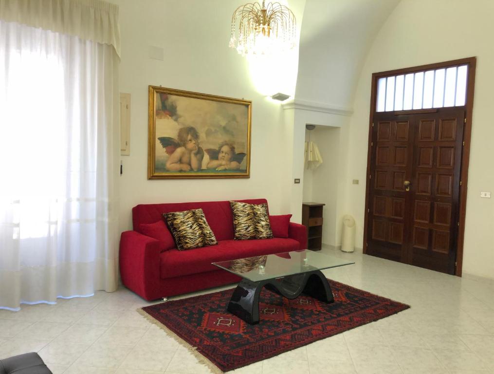ein Wohnzimmer mit einem roten Sofa und einem Tisch in der Unterkunft Dimora del '500 -City Apartment San Vito in San Vito dei Normanni