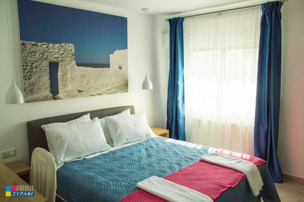 a bedroom with a bed and a window with blue curtains at Evaggelia Design Suite in Nea Peramos