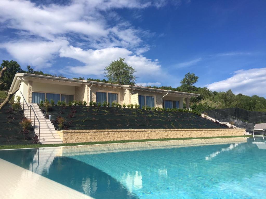 ein Haus mit einem Pool vor einem Haus in der Unterkunft Villa Brusadela Suites Garda in Garda