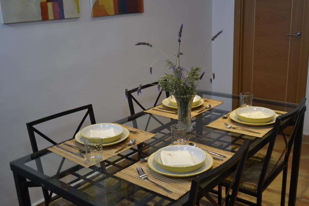 una mesa de comedor con sillas y platos y un jarrón en El Librero de La Alhambra, en La Zubia