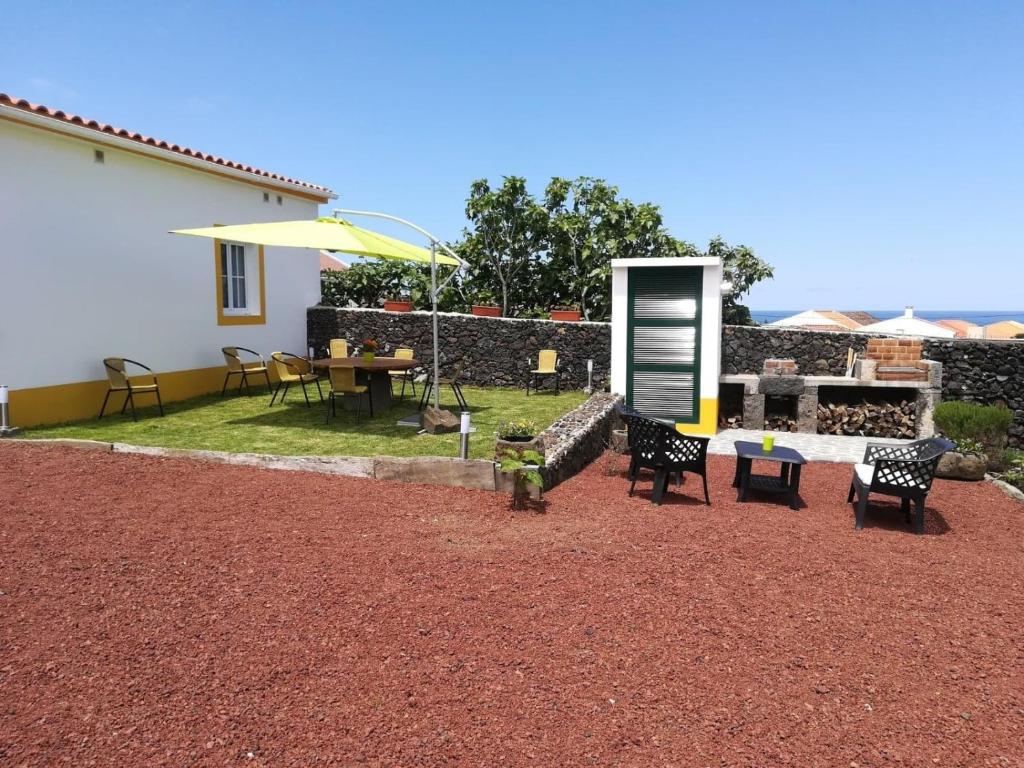 a patio with a table and chairs and an umbrella at Casa Neptuno in Rabo de Peixe