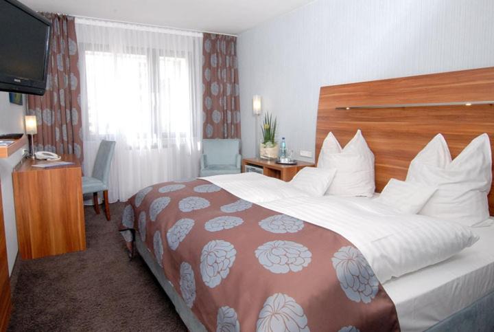 オッフェンバッハにあるホテル グラフの大型ベッドとテレビが備わるホテルルームです。