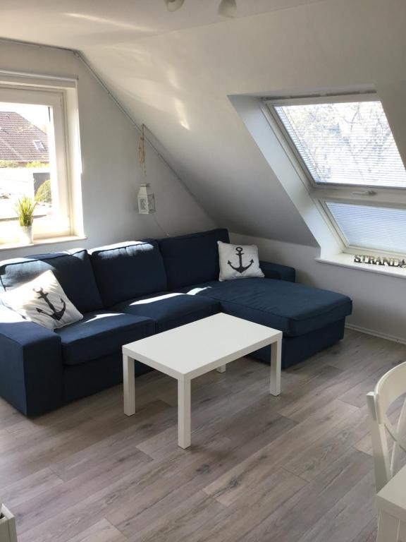 een woonkamer met een blauwe bank en een witte tafel bij Ferienwohnung Ankerplatz in Cuxhaven